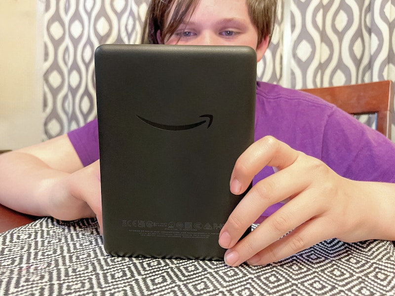 a teen reading on a kindle at the table