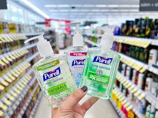 hand holding bottles of purell hand sanitizer