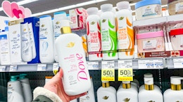 person holding dove serum body wash near other dove body washes with clearance signs for 50% off