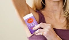 a woman holding a purple stick of deodorant