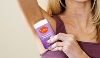 a woman holding a purple stick of deodorant