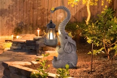 ILLUMINEW Solar Outdoor Garden Decor Elephant Statues Light sitting in a garden at dusk.
