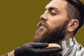 a man getting his beard brushed