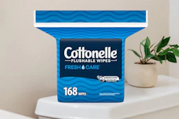 A 168-count pack of Cottonelle Flushable Wipes sits on a toilet tank.