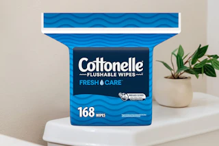 A 168-count pack of Cottonelle Flushable Wipes sits on a toilet tank.