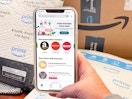 A cellphone displaying the ibotta app being held in front of Amazon boxes and packages