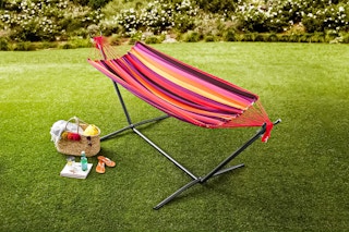 Lifestyle image of the multicolor Mainstays Freestanding Hammock in outdoor setting with picnic basket