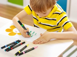 a kid coloring with acrylic makers at a table