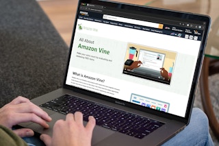 A person using a laptop to look at the Amazon website's page about Amazon Vine.