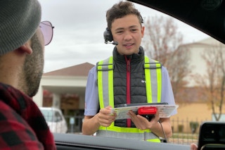 a teenager taking someone's order in the drive through at chick-fil-a