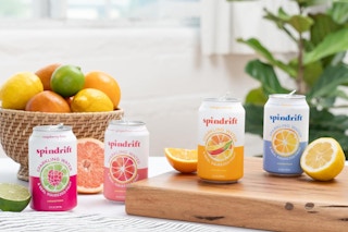 cans of sparkling water on a table with lemons, limes, and oranges