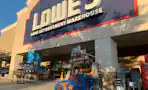 A dad and child in lowes car shopping cart walking into lowes store