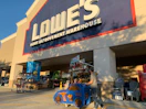 A dad and child in lowes car shopping cart walking into lowes store
