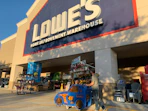 A dad and child in lowes car shopping cart walking into lowes store