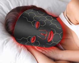 a person laying with a red light therapy mask