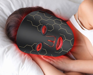 a person laying with a red light therapy mask