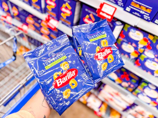 hand holding two bags of barilla tortellini pasta in walmart aisle