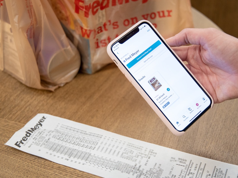 A person holding a smartphone above a receipt to take a photo for the ibotta rebate app.