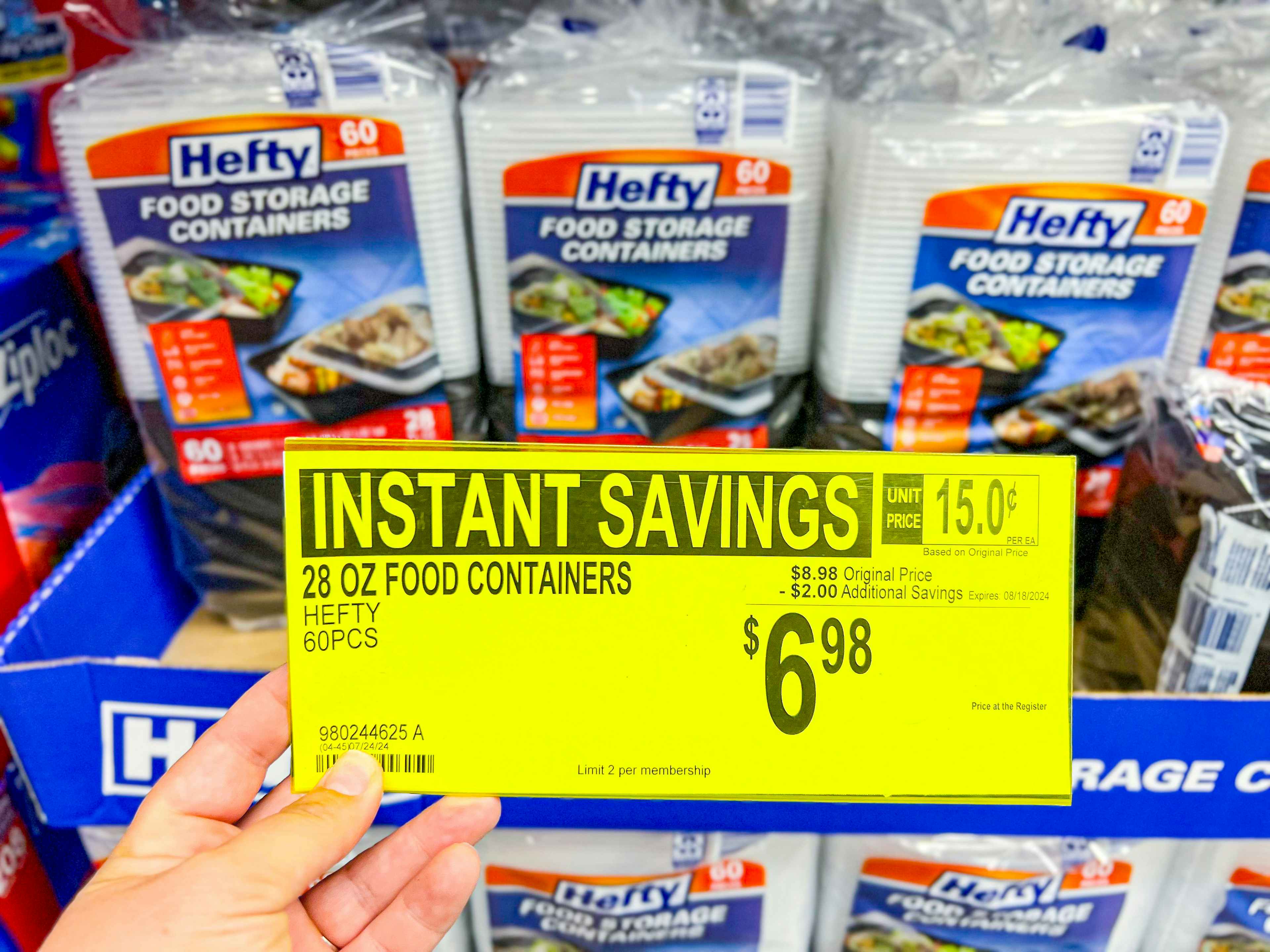 person holding a sign for $6.98 in front of hefty food storage containers