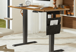 a wooden and black metal standing desk in a room with a monitor and decor