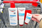 hand grabbing eucerin lotion products in a shopping cart