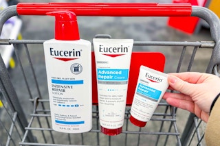 hand grabbing eucerin lotion products in a shopping cart