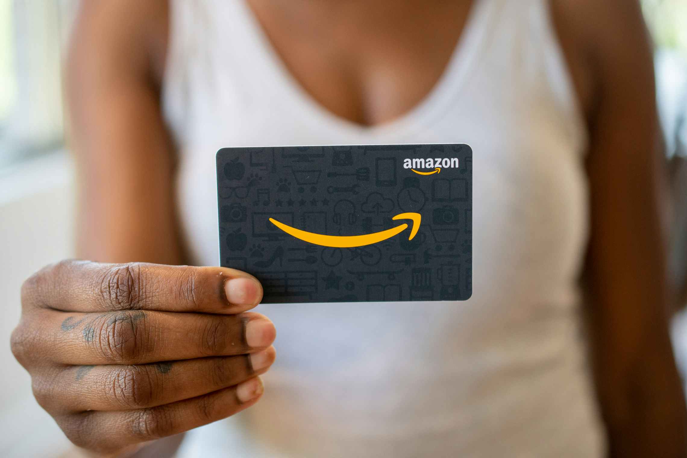 A woman holding an Amazon gift card.