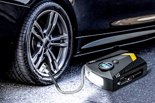 Lifestyle image of the Qunler Tire Inflator being used to pump up a vehicle tire