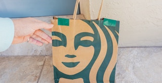 Someone picking up their Starbucks order that was dropped off at their front door