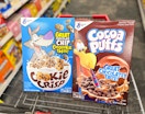 one box of Cocoa Puffs cereal and one box of Cookie Crisp cereal inside shopping cart