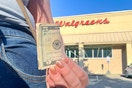 person holding $5 bill in front of walgreens store