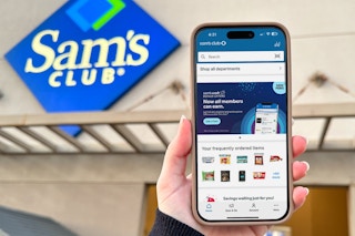 Someone holding up a phone displaying the Sam's Club app in front of a Sam's Club