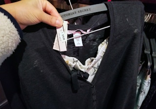 Hand holding out tags on a Victoria's Secret product