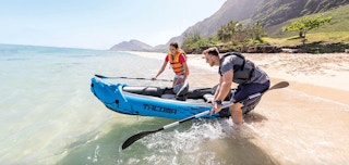 a couple going into the water with a kayak