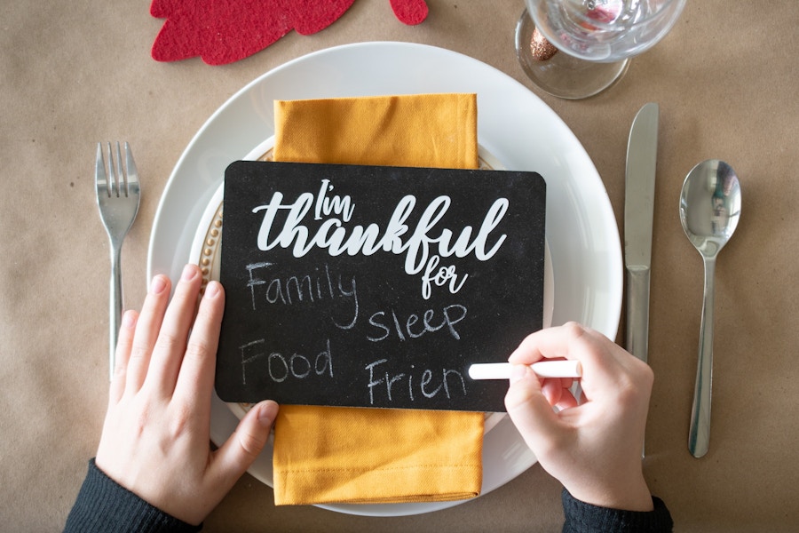 A person using chalk to write on a small chalk board that says "I'm thankful for".