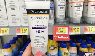 A hand holding Neutrogena sunscreen in a store aisle.