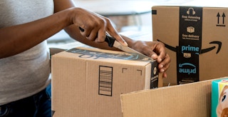 person using knife to open amazon box inside