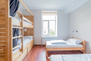 An empty college dorm room with bunkbeds and single bed with a window.
