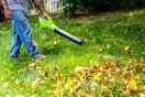 Lifestyle image of someone using the Greenworks 24V Cordless Axial Blower to blow fall leaves 