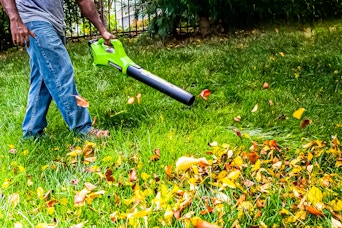 Lifestyle image of someone using the Greenworks 24V Cordless Axial Blower to blow fall leaves 