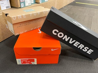 Converse, Nike, and TOMS shoe boxes stacked up on the floor inside DSW.