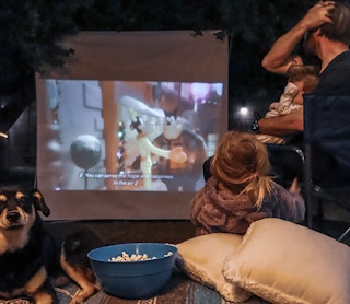 people watching a movie on a projector screen outside