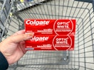 hand holding colgate toothpaste in walgreens cart
