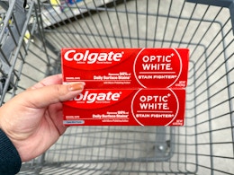 hand holding colgate toothpaste in walgreens cart
