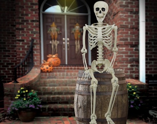 stock photo of way to celebrate five foot skeleton staged on a barrel in the front yard