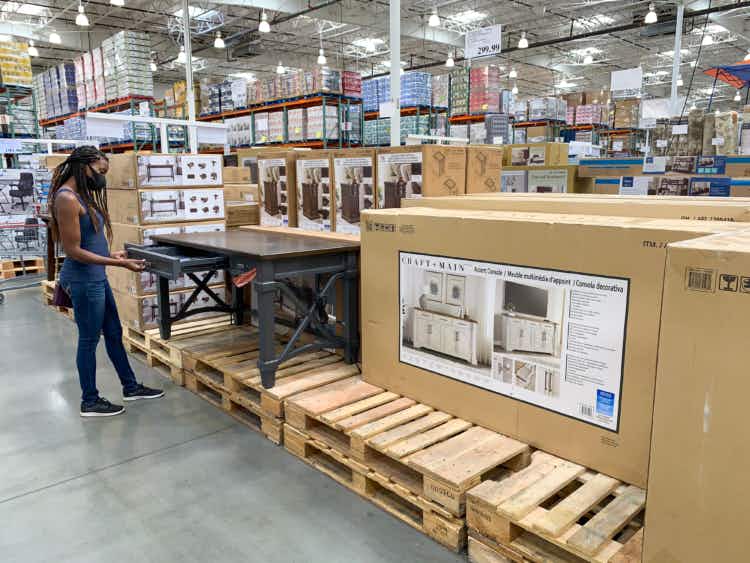 A woman looking at a desk among other furniture at Costco.