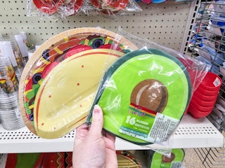 person holding a pack of taco themed paper plates and avocado themed napkins