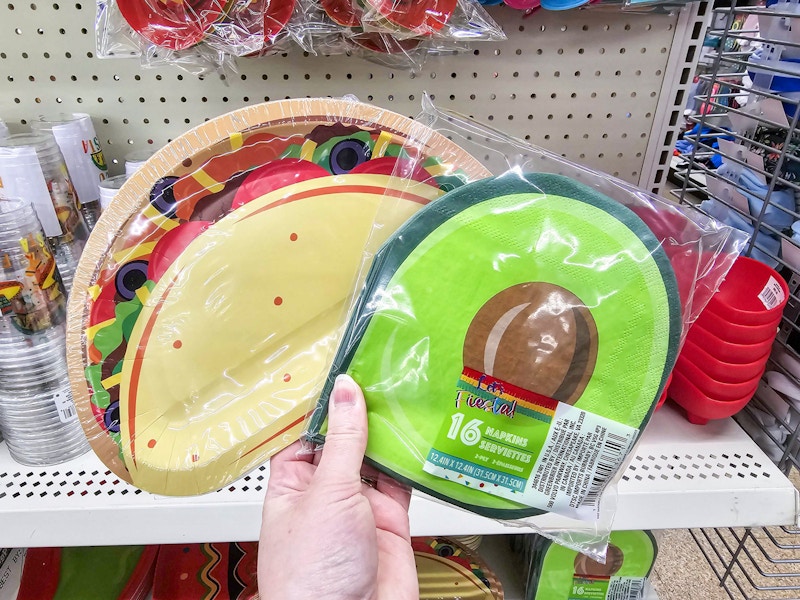 person holding a pack of taco themed paper plates and avocado themed napkins