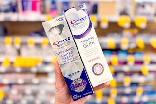 person holding crest gum and brilliance toothpastes