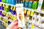 person holding a bottle of pantene shampoo in front of the shampoo shelves